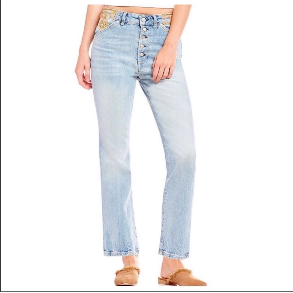 Free People boot cut jeans with pink and gold embroidery.